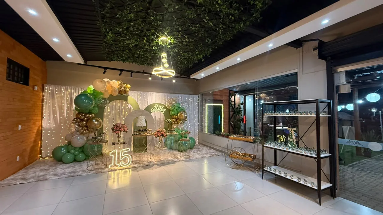 Salão decorado para 15 anos com balões verdes e o número iluminado