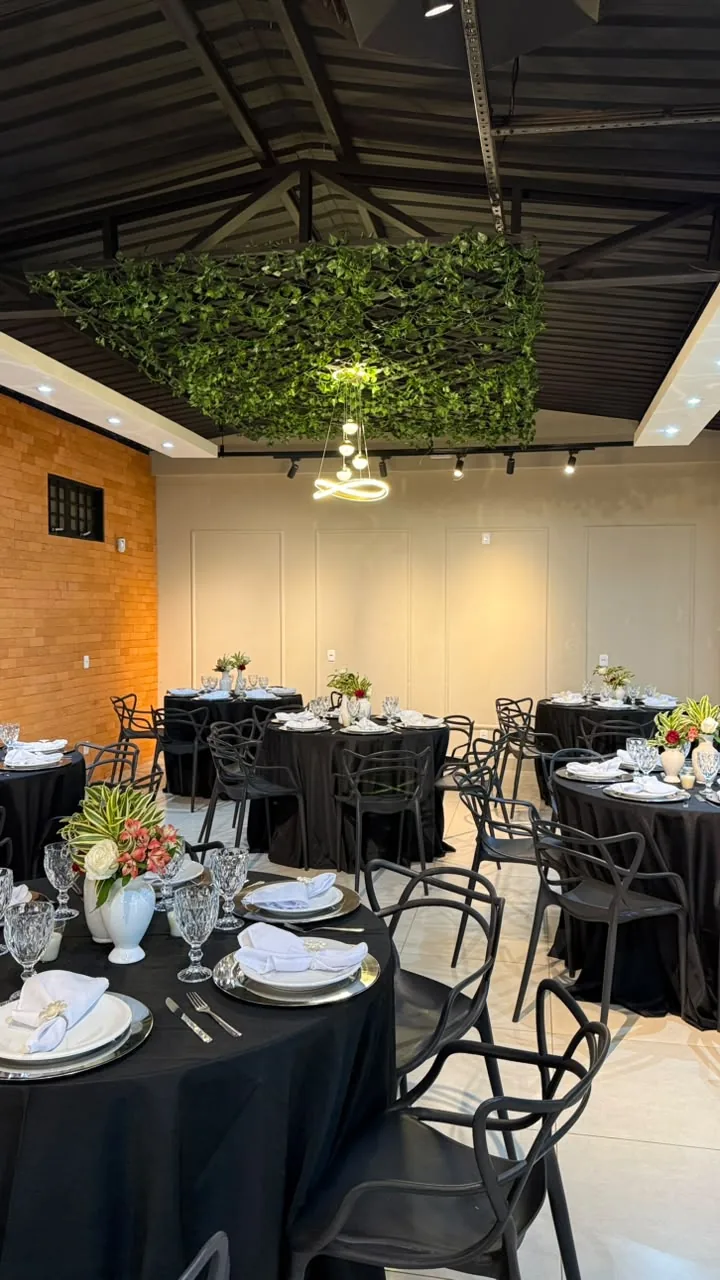 Salão com mesas de toalha preta postas para um evento adulto