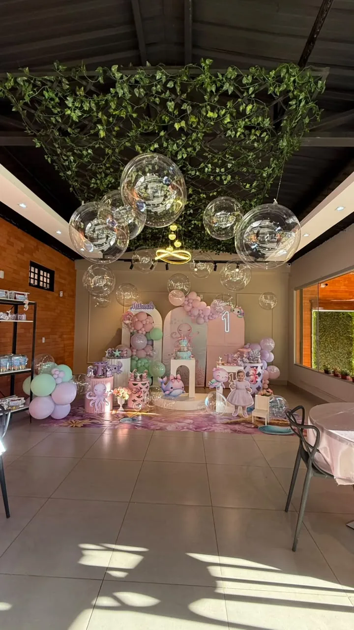 Salão decorado com balões em tons pastel sob o teto de folhagem