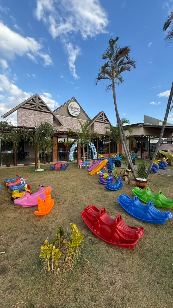 Gramado com brinquedos de balanço coloridos diante da fachada